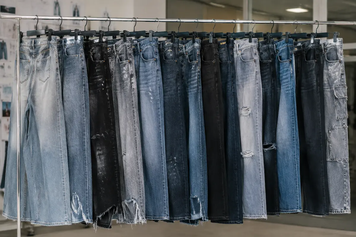 Range of denim washes and fits on a factory rack, from light stone wash to black and distressed styles