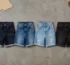 Custom denim shorts manufacturer cutting table with four denim shorts in raw indigo, stone wash, distressed light blue and black